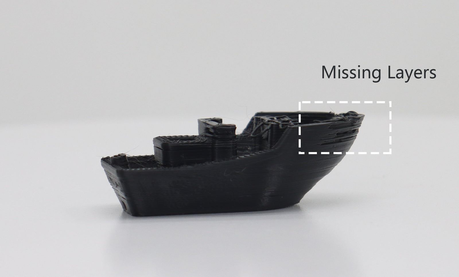 Black 3D Benchy model with a highlighted box showing missing layers on the hull, illustrating under-extrusion print defects.