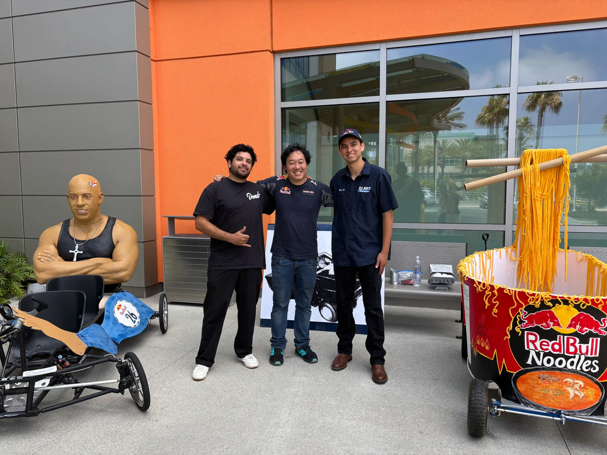 Three men pose for a photo at Red Bull Soapbox Race outdoor event