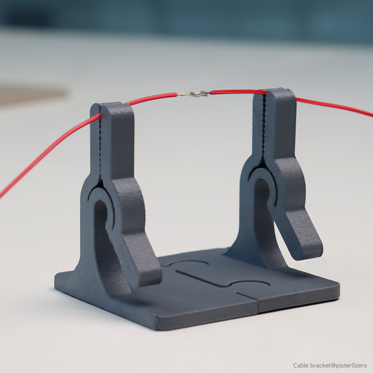 3D printed gray cable bracket holding red wire, ideal for electronics work.